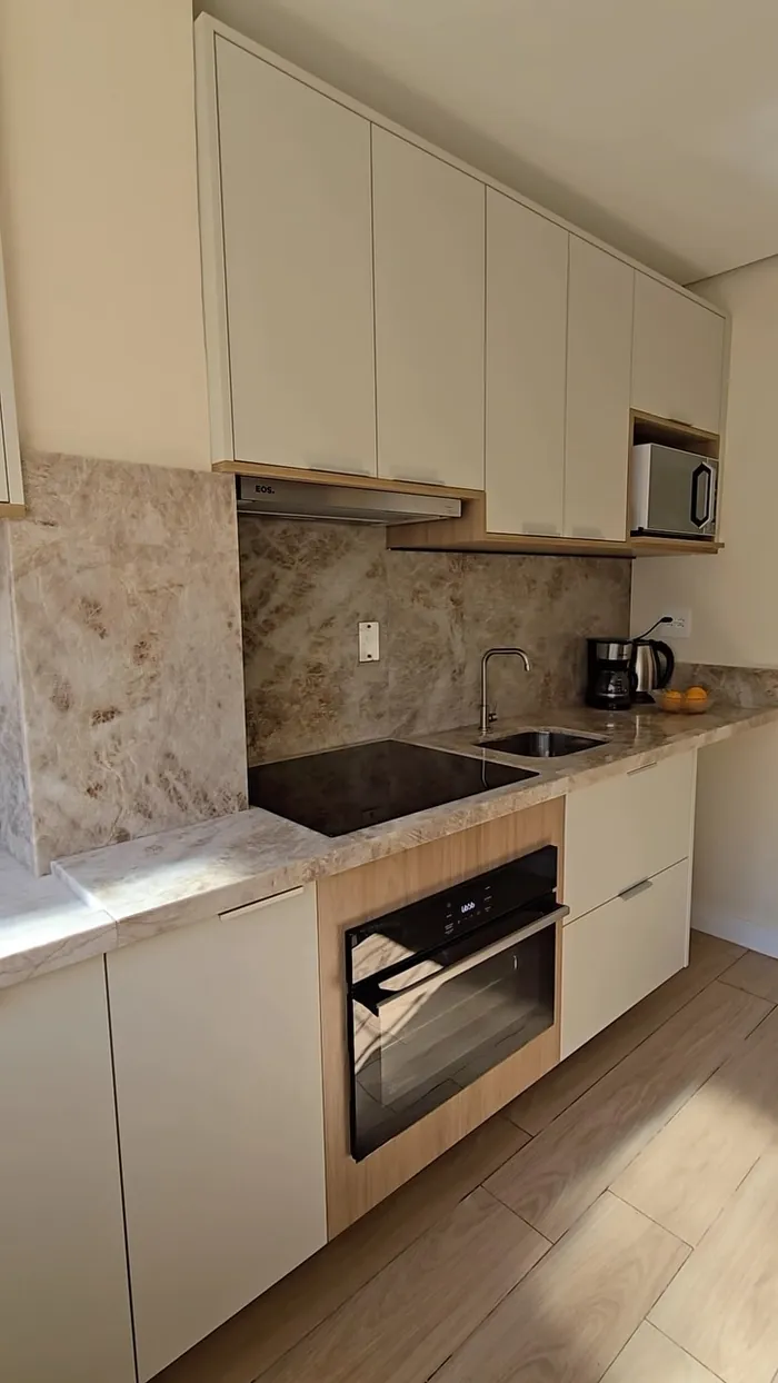 Cozinha planejada com armários off-white, detalhes em madeira e torre para forno
